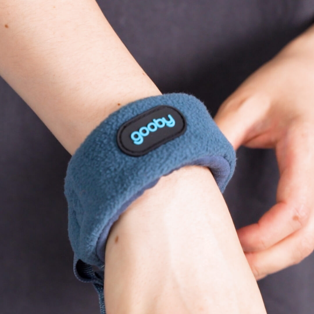 Close-up of a blue fleece wrist cuff with a Gooby logo being adjusted by hand