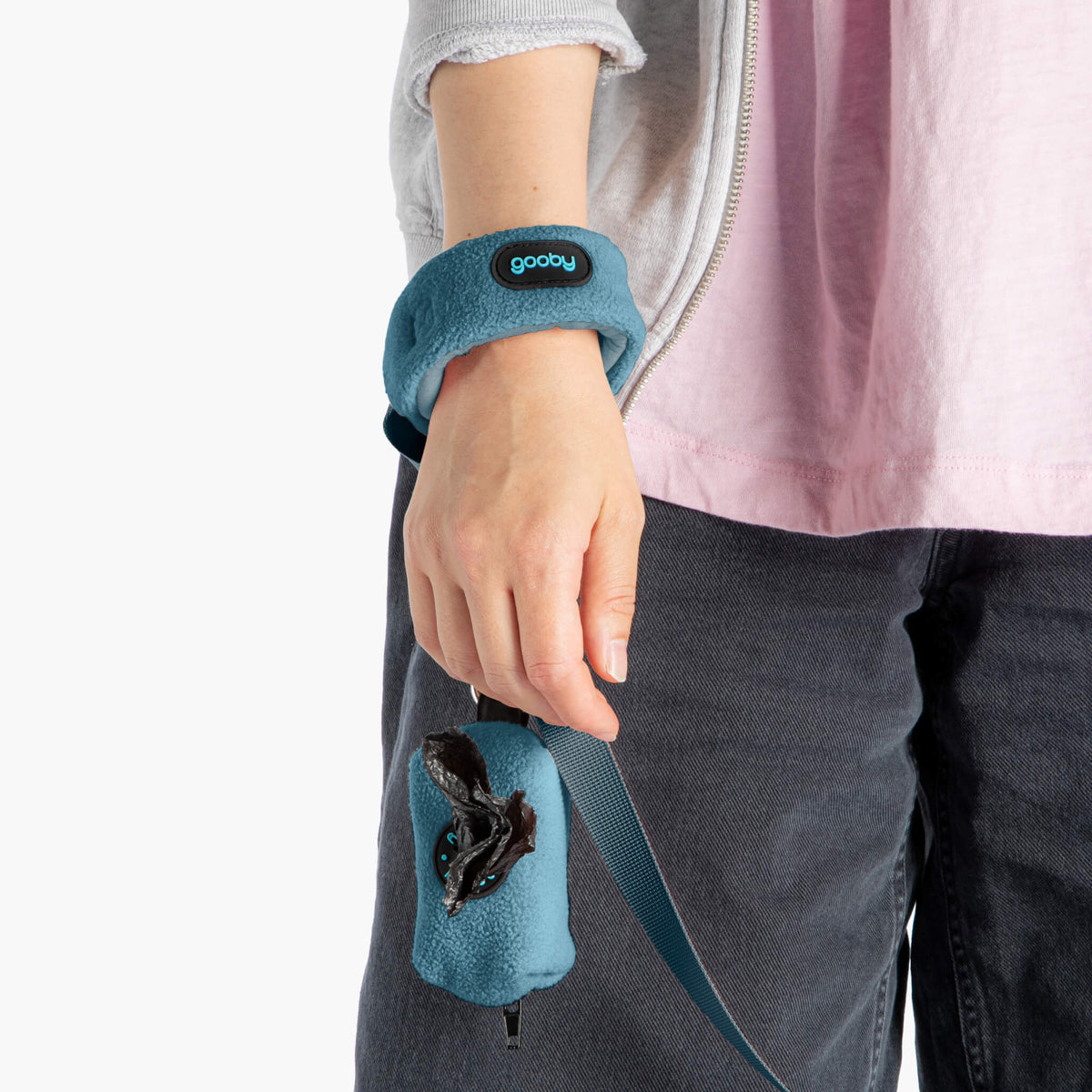 Close-up of a person wearing a blue wristband leash with a matching blue treat pouch