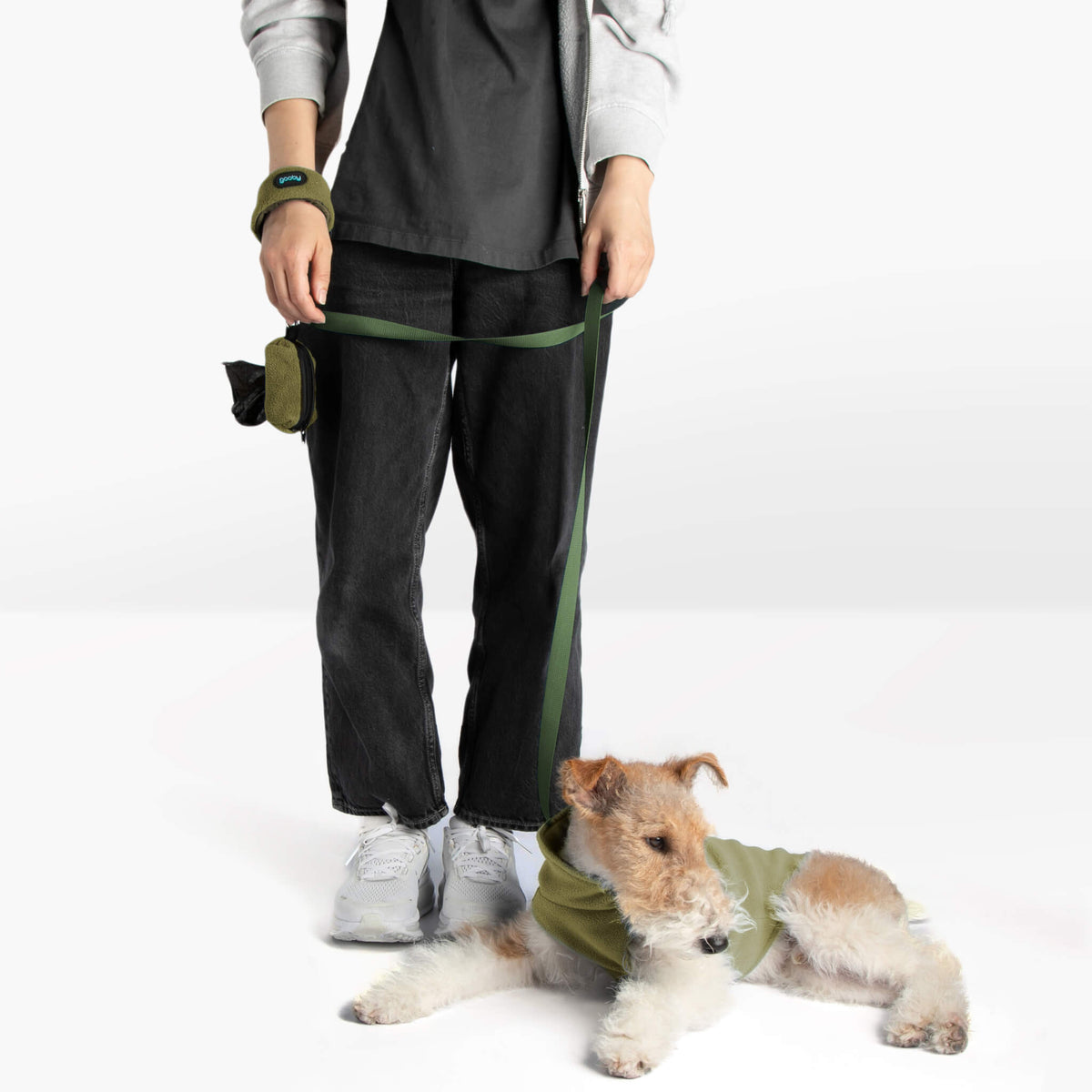 Dog wearing an olive zip-up fleece vest with a matching leash