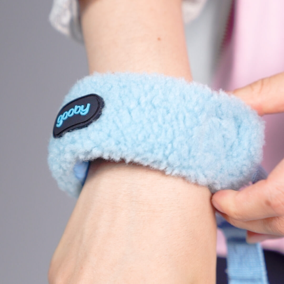 Close-up of a soft blue fleece cuff being fastened around a person's wrist