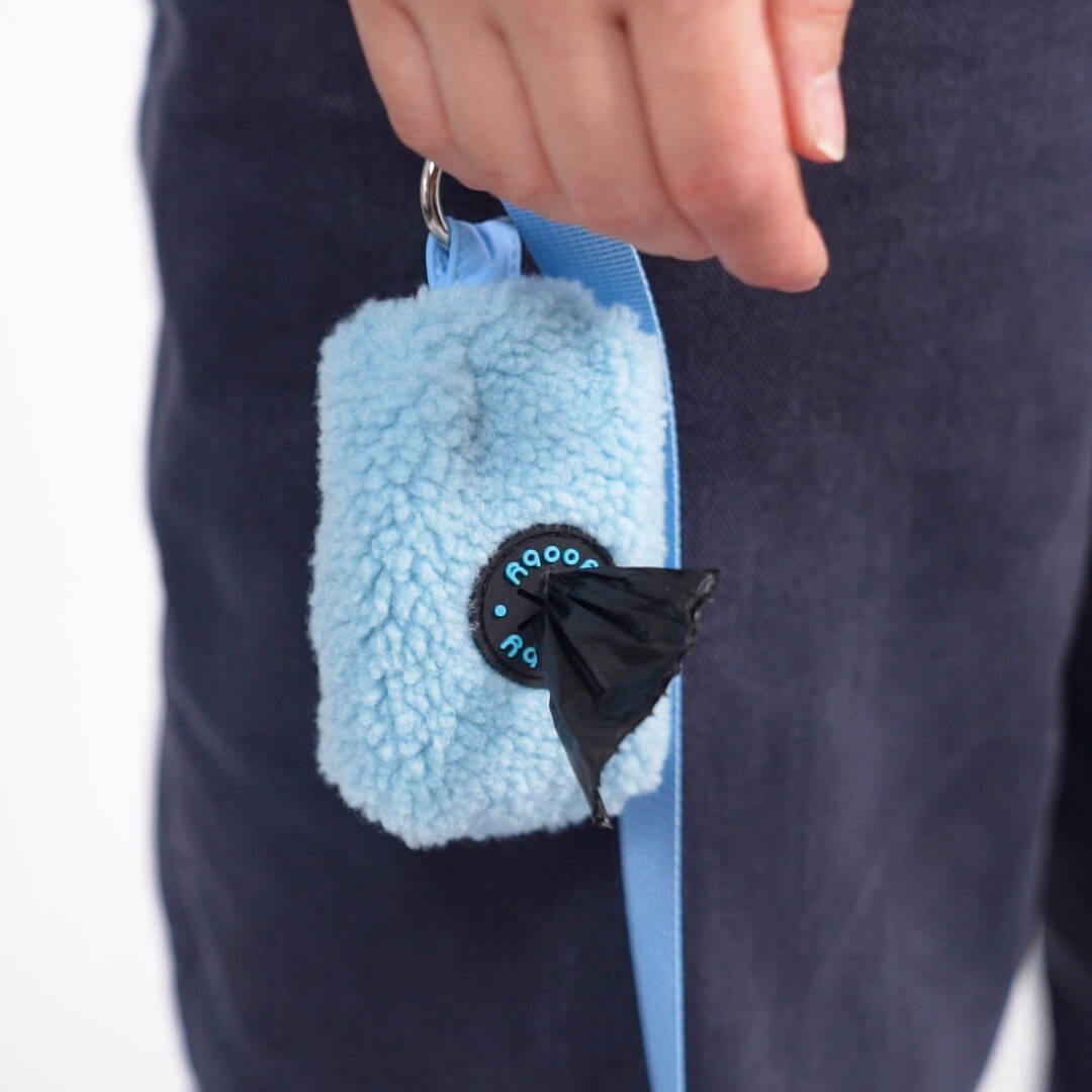 Close-up of a light blue fleece dog waste-bag dispenser attached to a blue leash