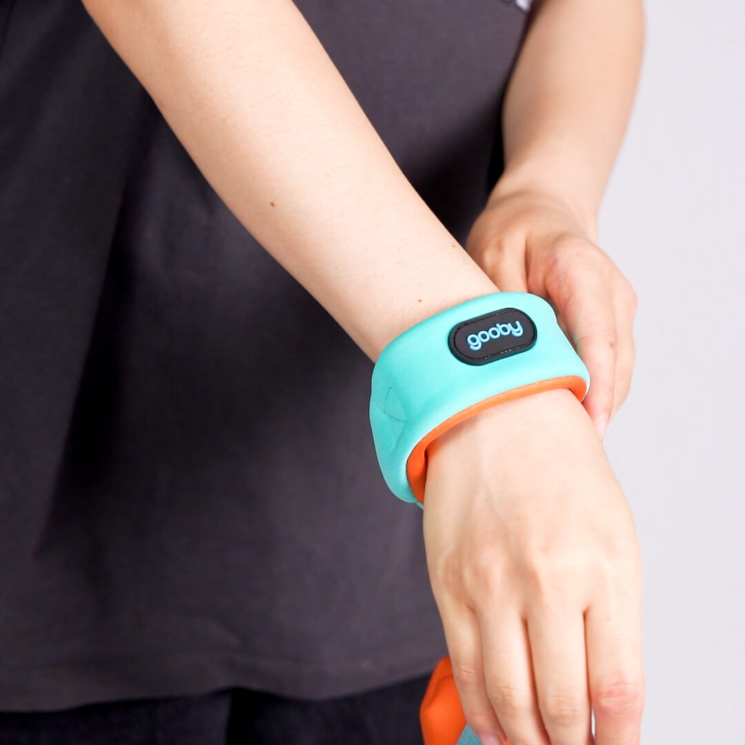 Close-up of a person wearing a turquoise wristband with orange trim and a black logo label
