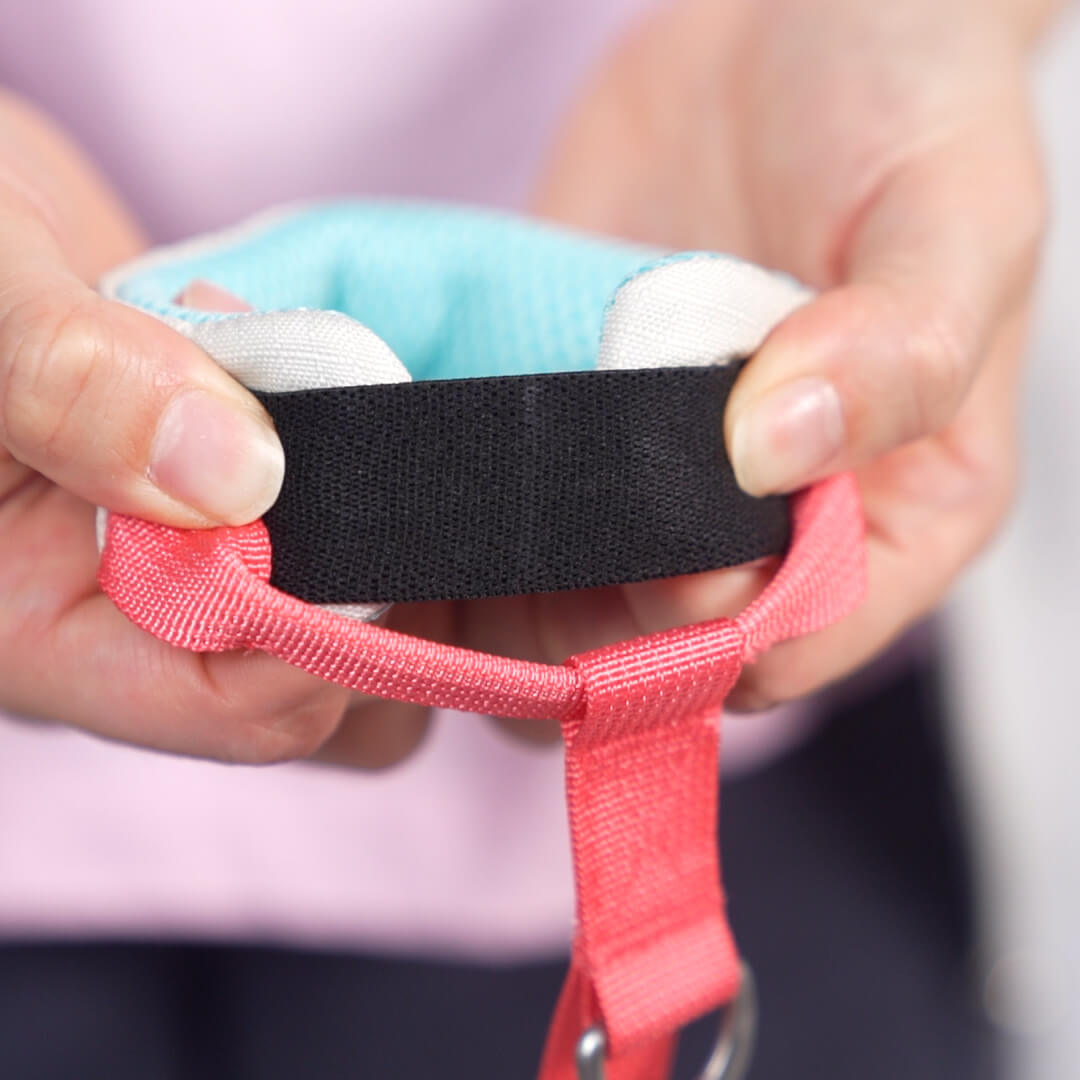 Hands adjust the black fastening strap on a coral and turquoise leash set