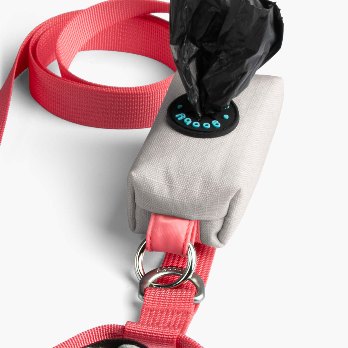 Close-up of a cream step-in harness with red webbing, metal rings, and a matching leash