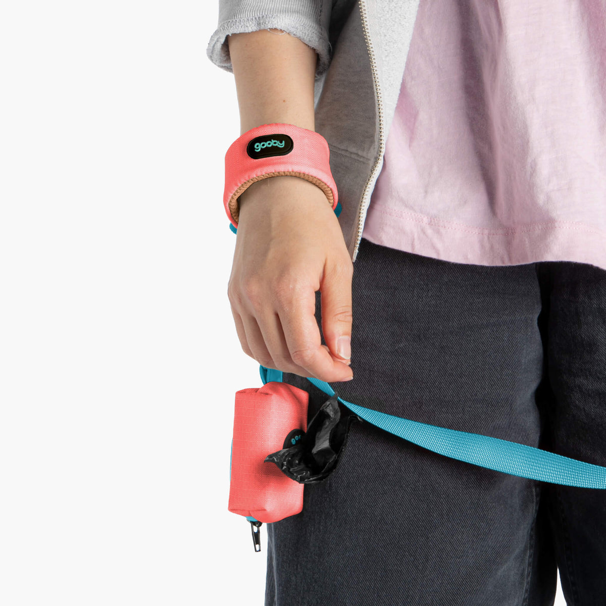 Close-up of a person wearing a pink wristband with a matching leash pouch and turquoise leash strap