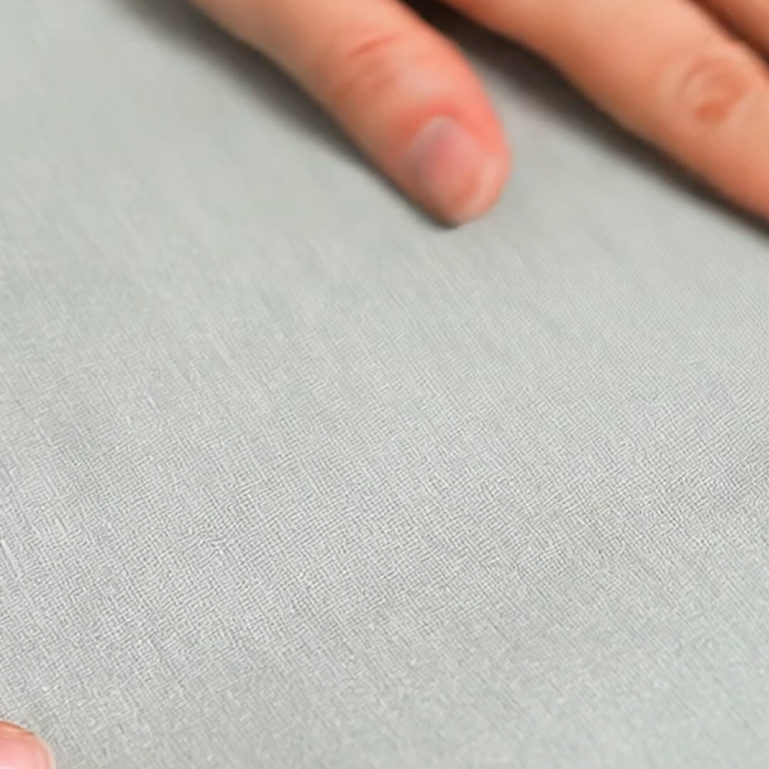 Close-up of pale gray textured fleece fabric with fingers resting on the surface