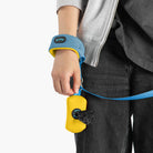Close-up of a sky blue wristband leash with a yellow accessory pouch on a person's hand