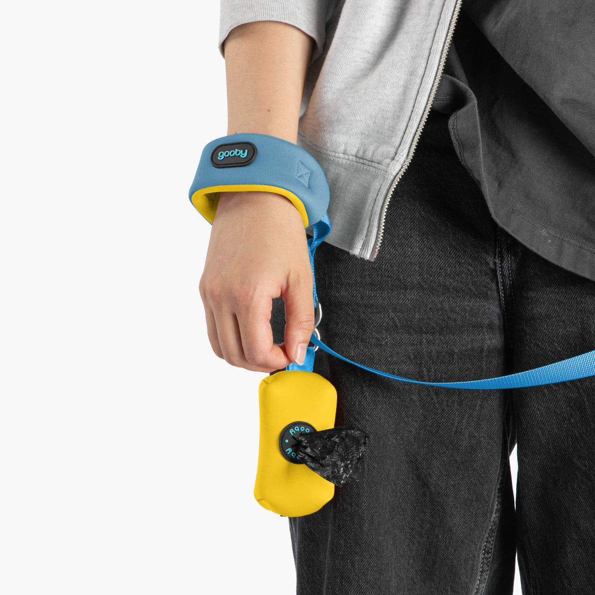 Close-up of a sky blue wristband leash with a yellow accessory pouch on a person's hand