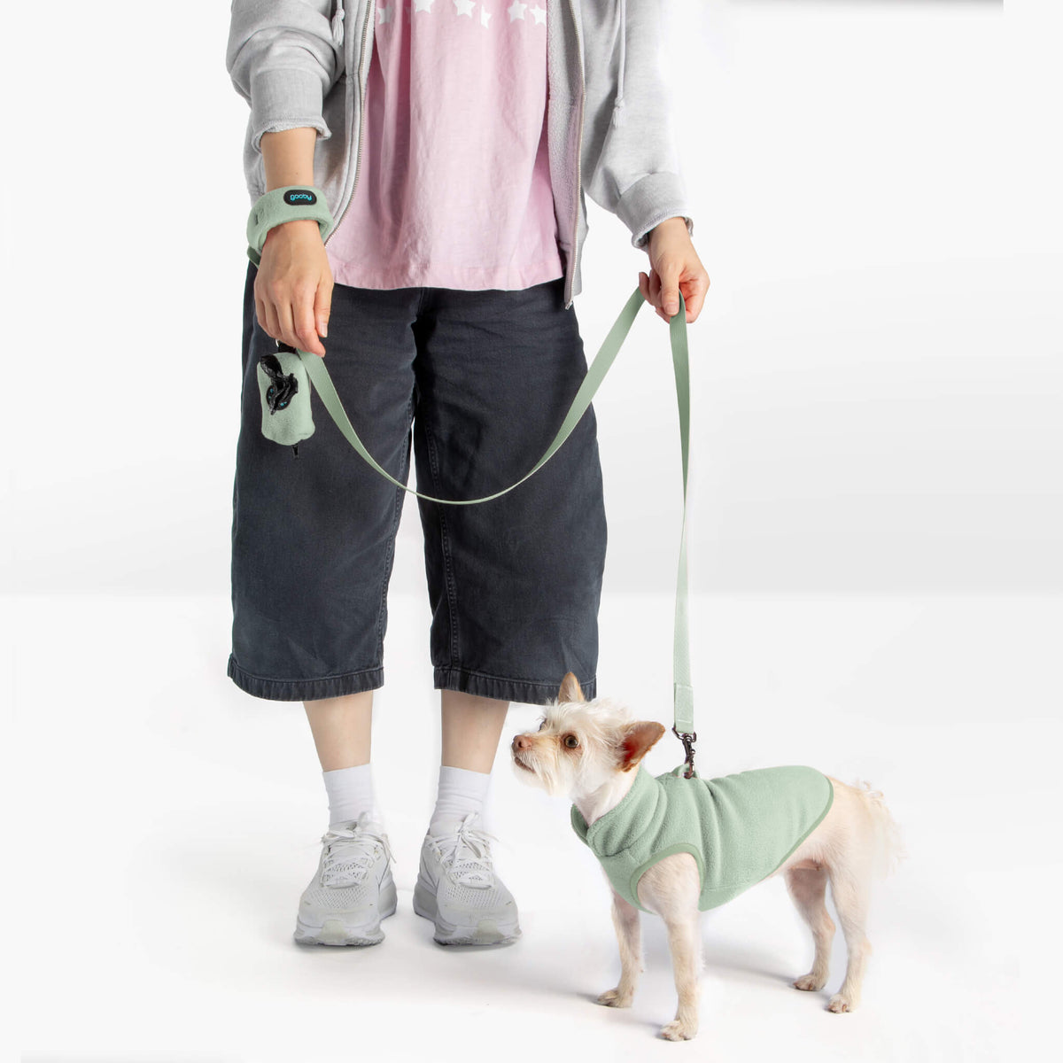 Person and small dog wearing matching mint fleece vests with a mint leash