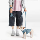 Dog wearing a steel blue fleece vest and matching leash beside a person