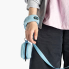 Close-up of a person holding a baby blue sherpa wristband leash with a matching zippered pouch