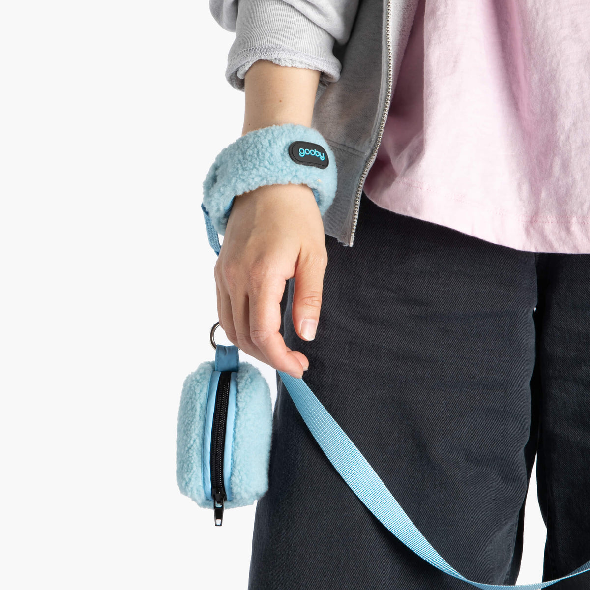 Close-up of a person holding a baby blue sherpa wristband leash with a matching zippered pouch