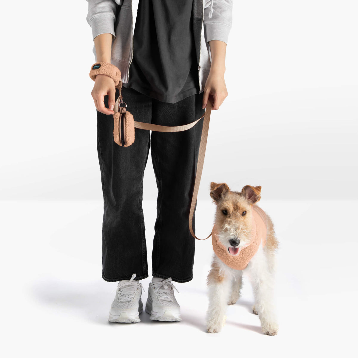 Person walking a dog with a tan matching leash and wrist strap