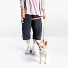 Person walking a small dog wearing a cream harness with a pink leash