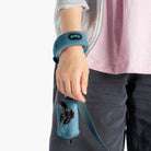 Close-up of a blue wristband leash and matching waste-bag holder worn with a fleece vest